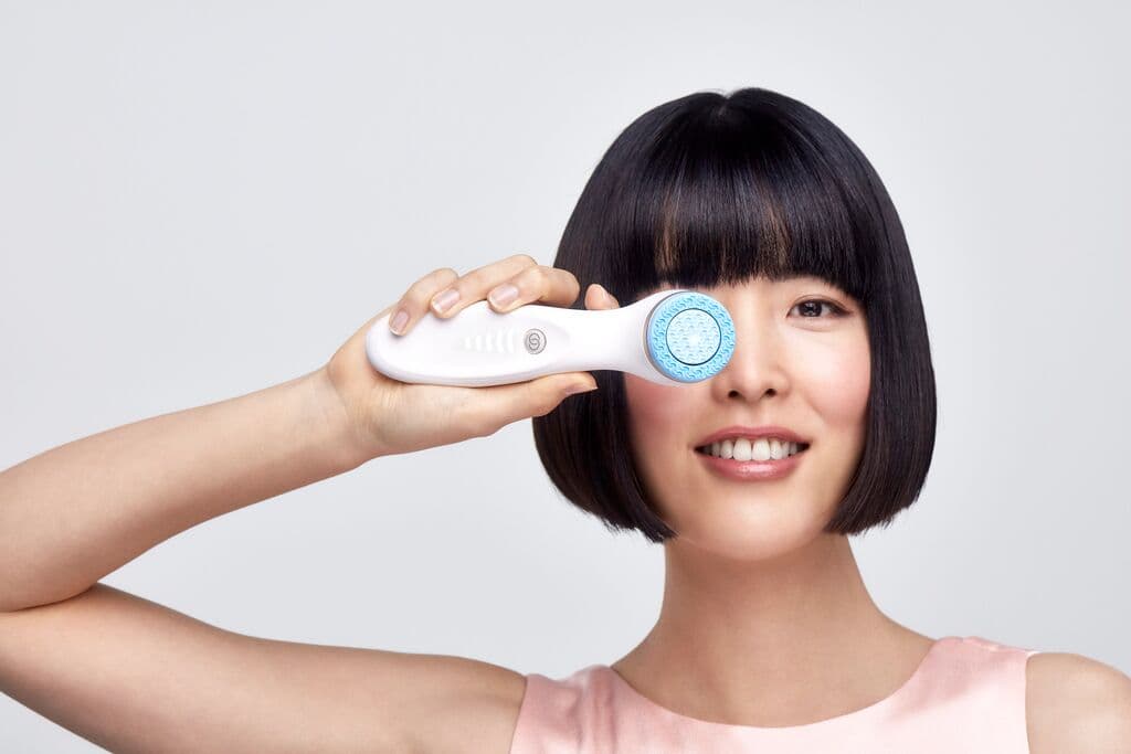 Woman using the ageLOC LumiSpa iO device as part of her skincare ritual